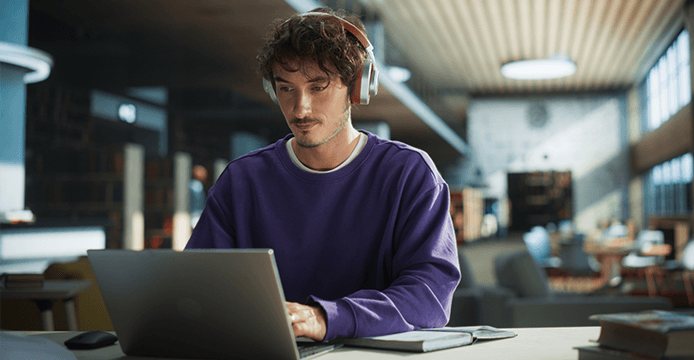 Man working at a laptop making notes