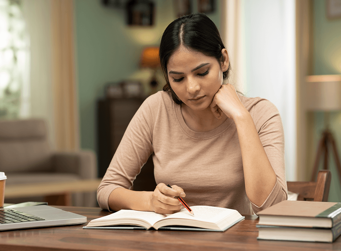 Woman studying at desk with notepad and pen