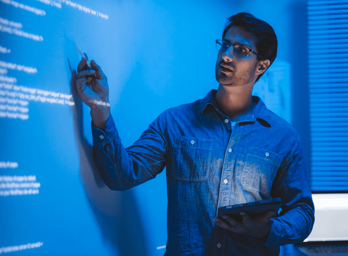 Man Pointing at Text on Smartboard